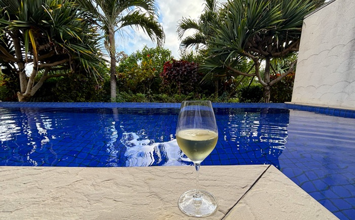 シギラミラージュ プールヴィラプレミアのプライベートプール。青い水面をバックに置かれたシャンパングラスと南国の木々