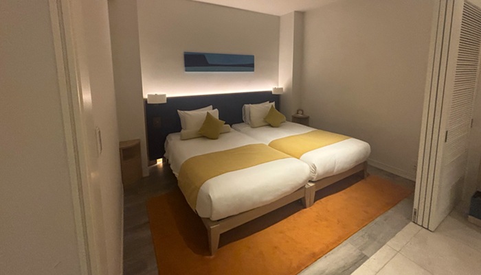 シギラミラージュ プールヴィラプレミア1階のベッドルーム。2台のベッドと足元のオレンジのラグが印象的な落ち着いた空間