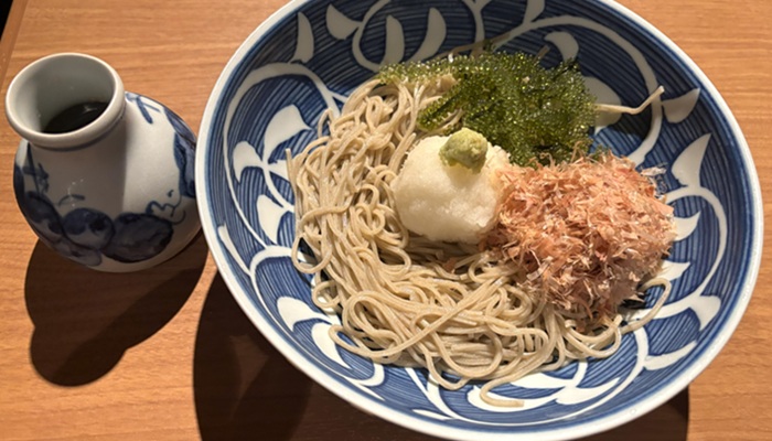 シギラミラージュ近くの蕎麦居酒屋「彩海」で提供される、海ぶどう蕎麦。日本蕎麦の上に、沖縄特産の海ぶどう、大根おろし、鰹節が乗り、小徳利が添えられている